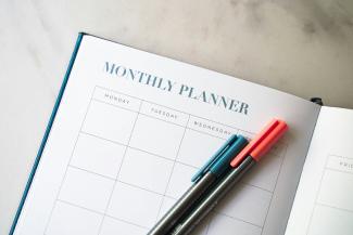 a planner with two pens sitting on top of it by 2H Media courtesy of Unsplash.