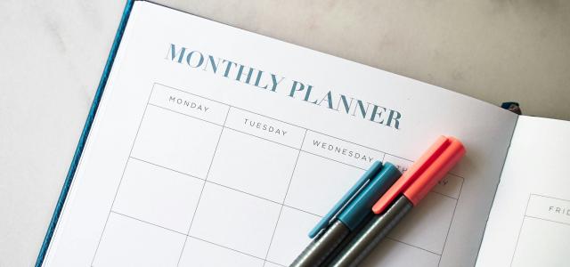 a planner with two pens sitting on top of it by 2H Media courtesy of Unsplash.
